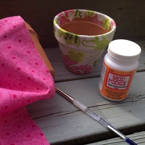 Decorating clay pots with Mod Podge.