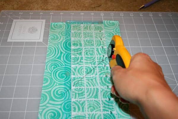 Cutting fabric on a rotary cutter with a ruler on a craft mat
