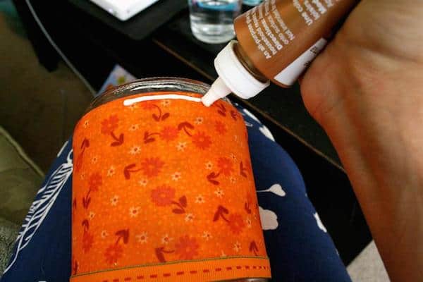 Placing a line of craft glue on the fabric wrapped jar