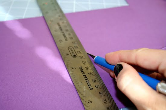 Cutting the purple paper with a craft knife and ruler