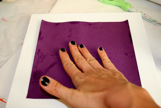 Smoothing the purple paper down onto the canvas