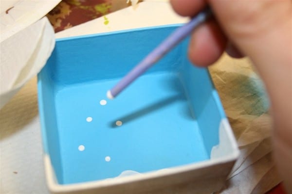 Making dots with a paintbrush handle on the back of the paper mache box