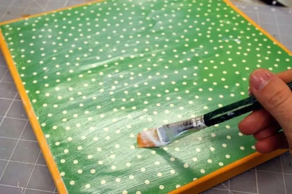 Attach scrapbook paper to a square canvas with Mod Podge
