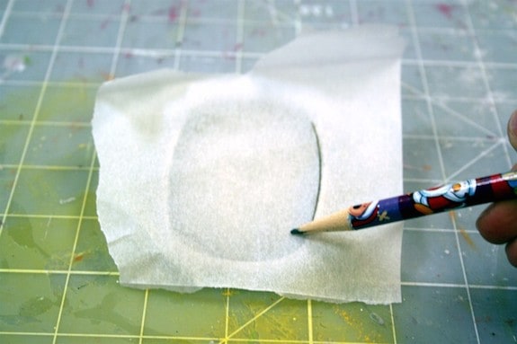 Using a pencil and tracing paper to create a template of the belt buckle