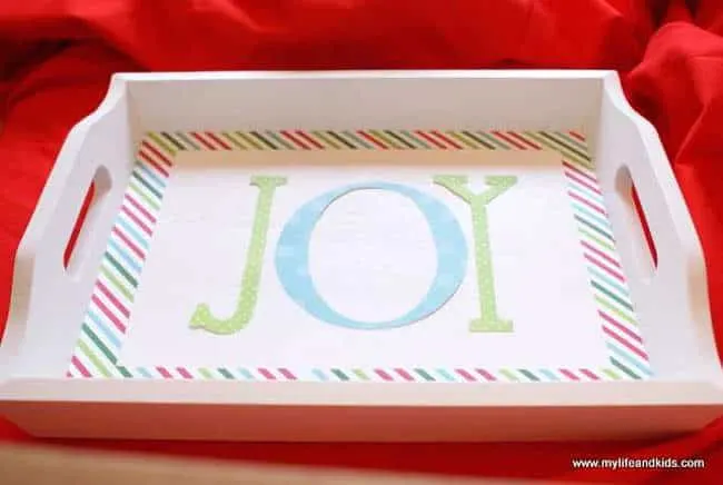 Paper letters spelling JOY laying on the white tray