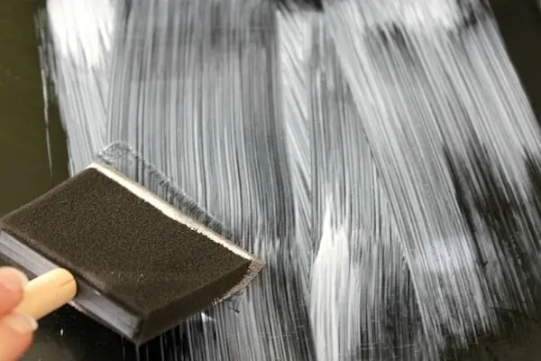 Close up of applying Mod podge to a table with a foam brush