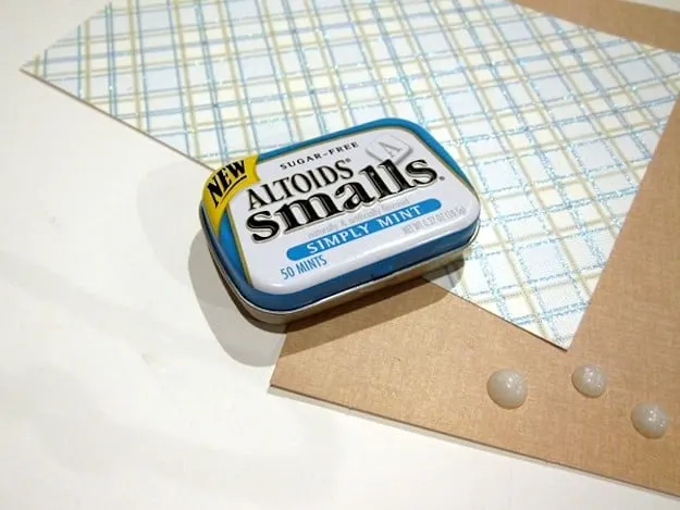 Altoids container on top of sheets of scrapbook paper