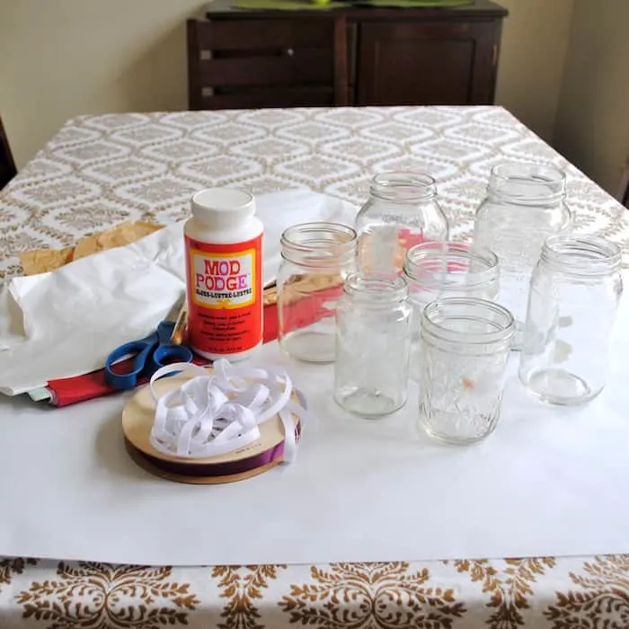 Glass jars, tissue paper, Mod Podge Gloss, scissors, and ribbon