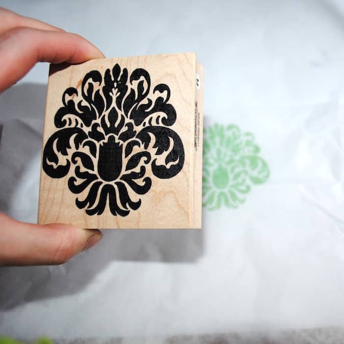 Stamping a piece of tissue paper with an ornate stamp