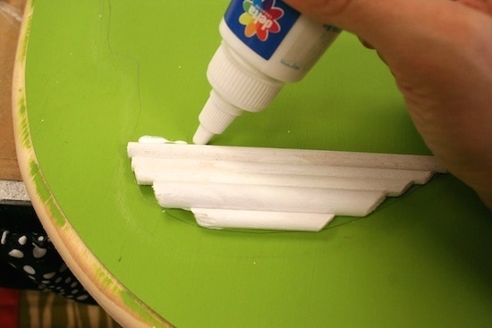 Gluing dowel rods to the wood plaque with craft glue