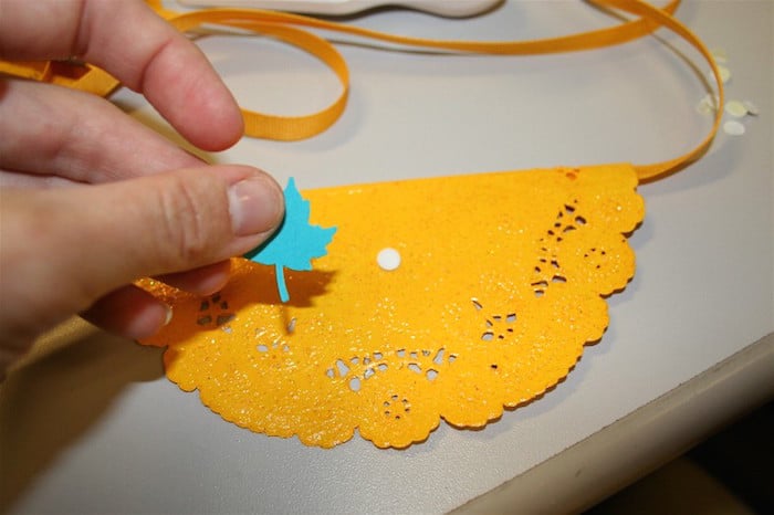 Adding paper leaves to the doilies with a pop dot