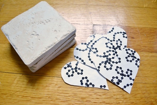 Four stone tiles and four hearts cut out of scrapbook paper