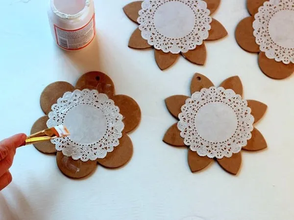 Using a brush to Mod Podge a doily to the top of a spring garland