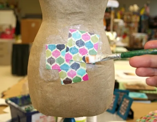 Adhering fabric scraps to the dress form with a paint brush and Mod Podge