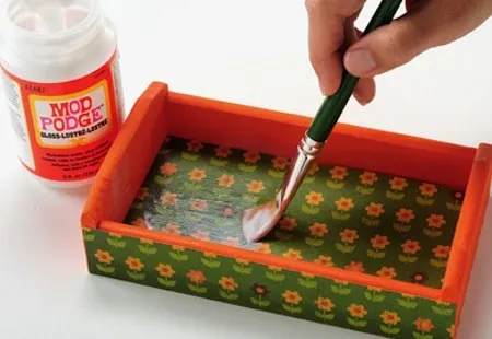 Painting a top coat of Mod Podge on the inside of a tray