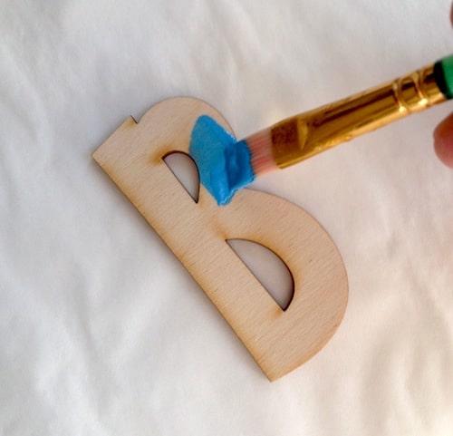 Painting a wood letter B with blue paint
