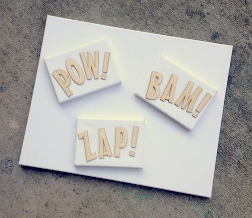 Large canvas with three small canvases on top and wood letters that spell POW, BAM, and ZAP