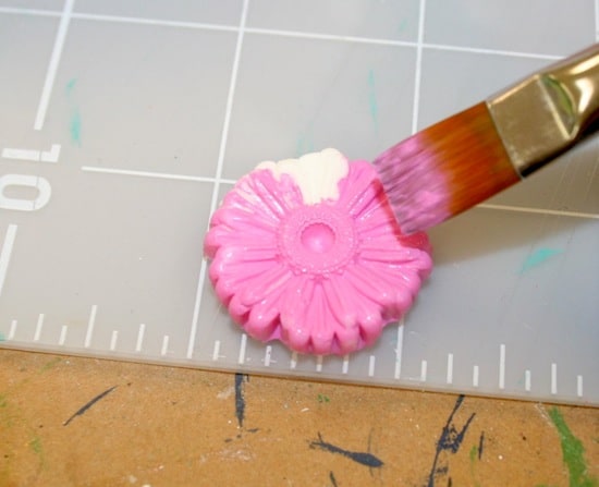 Painting a scrapbook embellishment with pink acrylic paint