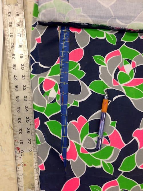 Using a ruler and craft knife to cut floral fabric into thin strips