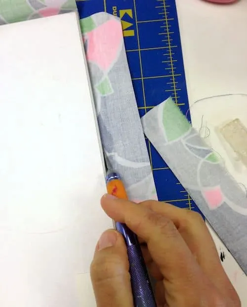 Trim fabric pieces from the mirror with a craft knife