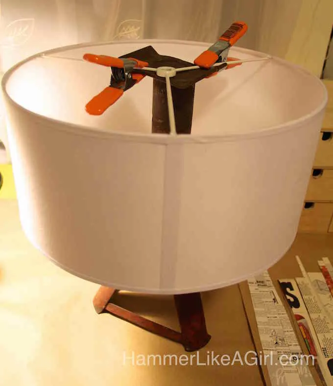 White drum lampshade clamped to a car jack