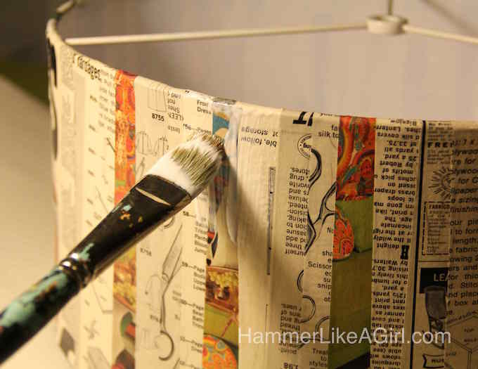 Applying Mod Podge to the outside of the decoupage lampshade with a paintbrush