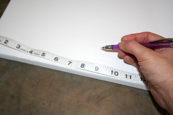 Marking four sections on a canvas with a pencil and measuring tape