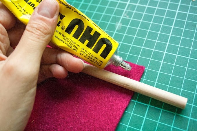 Glue being applied to the top of a piece of felt underneath a dowel rod