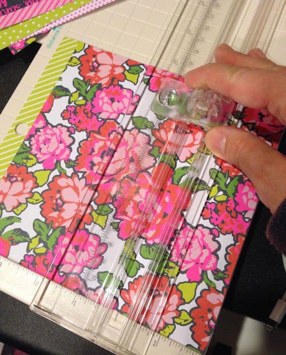 Using a paper cutter on a piece of floral scrapbook paper