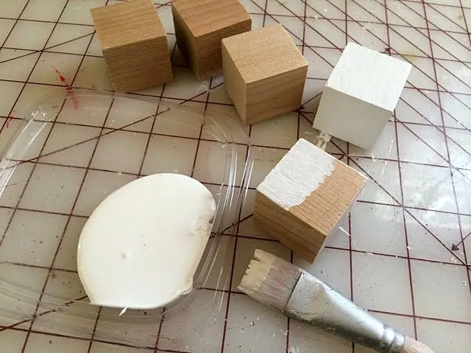 Painting wood blocks with white acrylic craft paint using a paintbrush