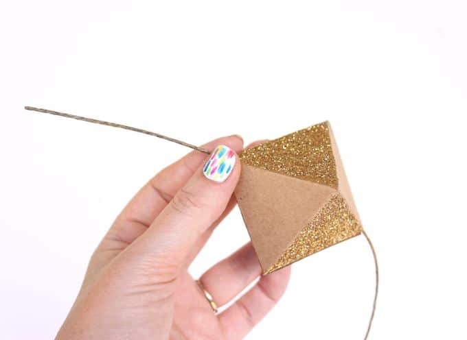 Hand holding a paper octahedron piece sprinkled with gold glitter
