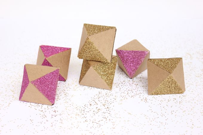 Pieces of paper folded into octahedrons with gold and pink glitter 
