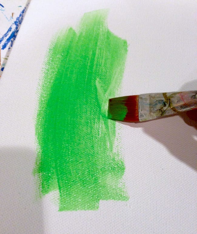 Painting a canvas with bright green paint