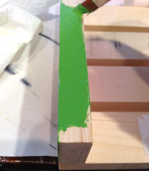 Painting the bottom of a wood plant stand with green craft paint