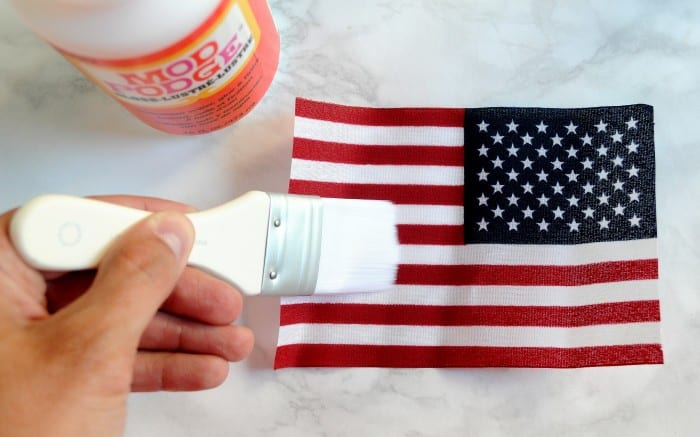 Applying Mod Podge to the back of a flag