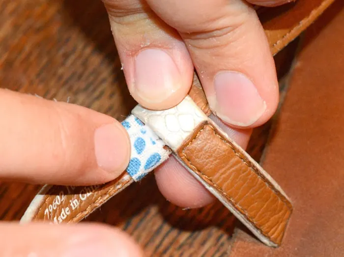 Fingers showing the inside of a sandal strap with the fabric attached