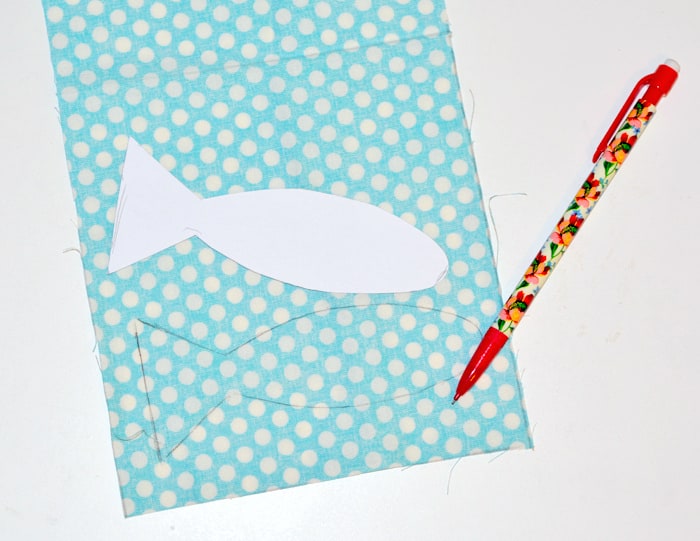 Tracing a fish shape onto a polka dot fabric with a pencil