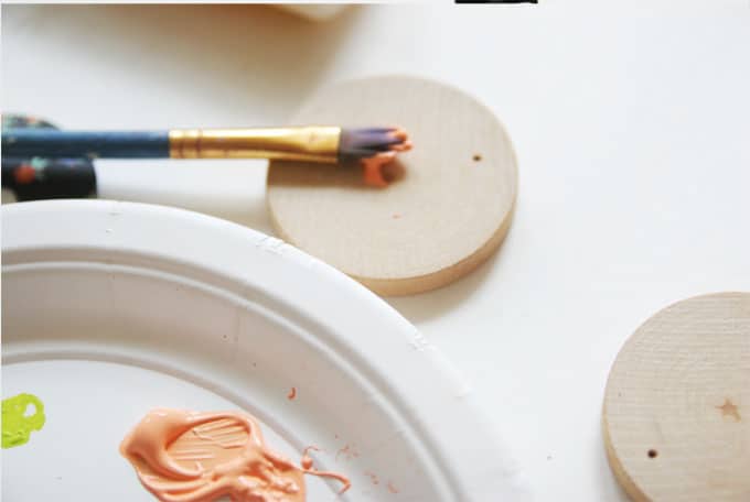 Painting wood circles with acrylic paint and a paintbrush