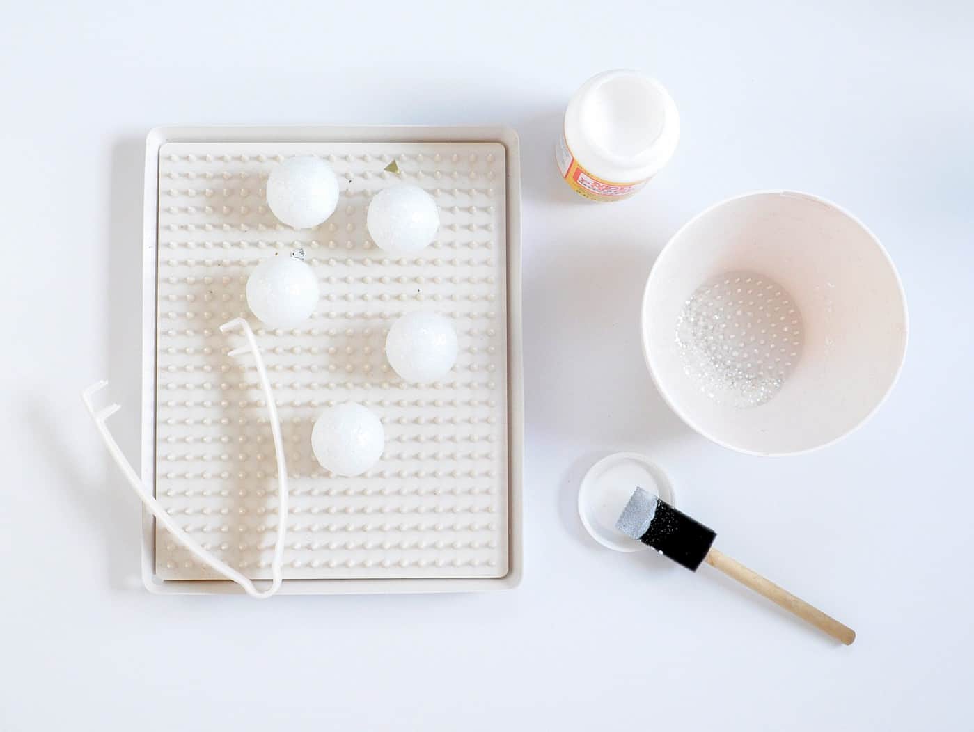 Covering ping pong balls in glitter with Mod Podge