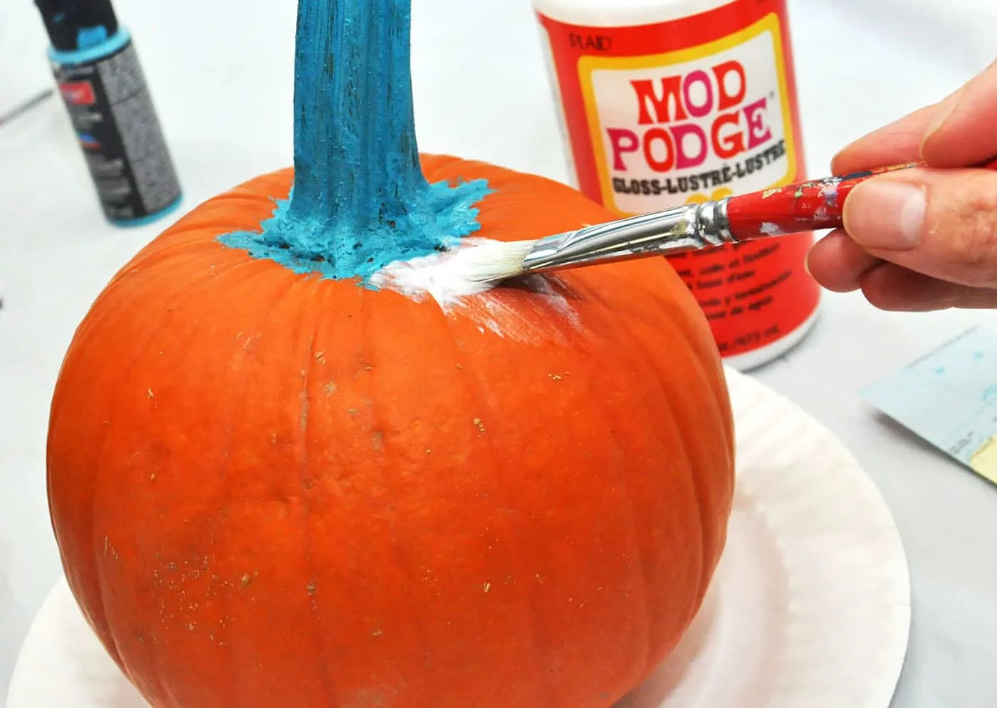 Applying Mod Podge to a pumpkin