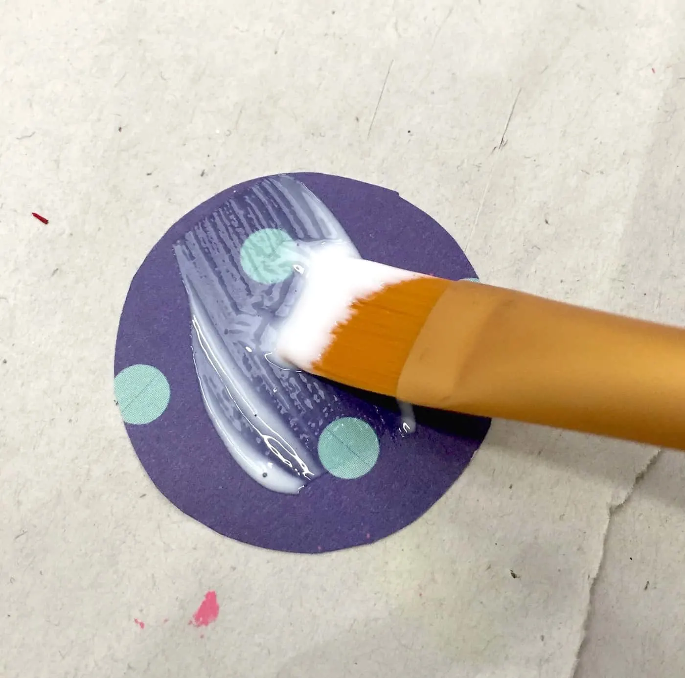 Medium layer of Mod Podge applied to a circular piece of scrapbook paper