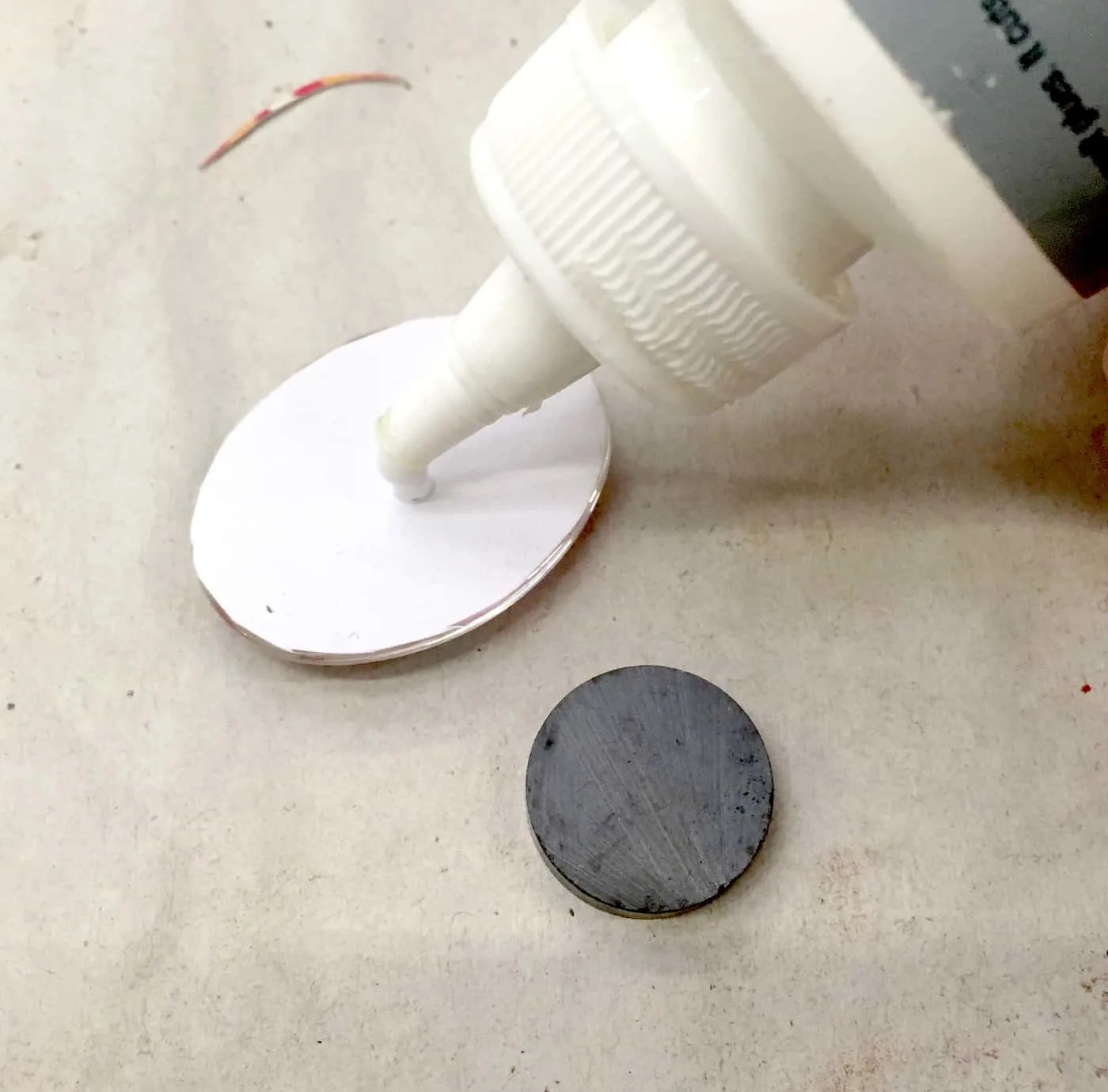 Magnet being glued to the back of a glass dome with craft glue