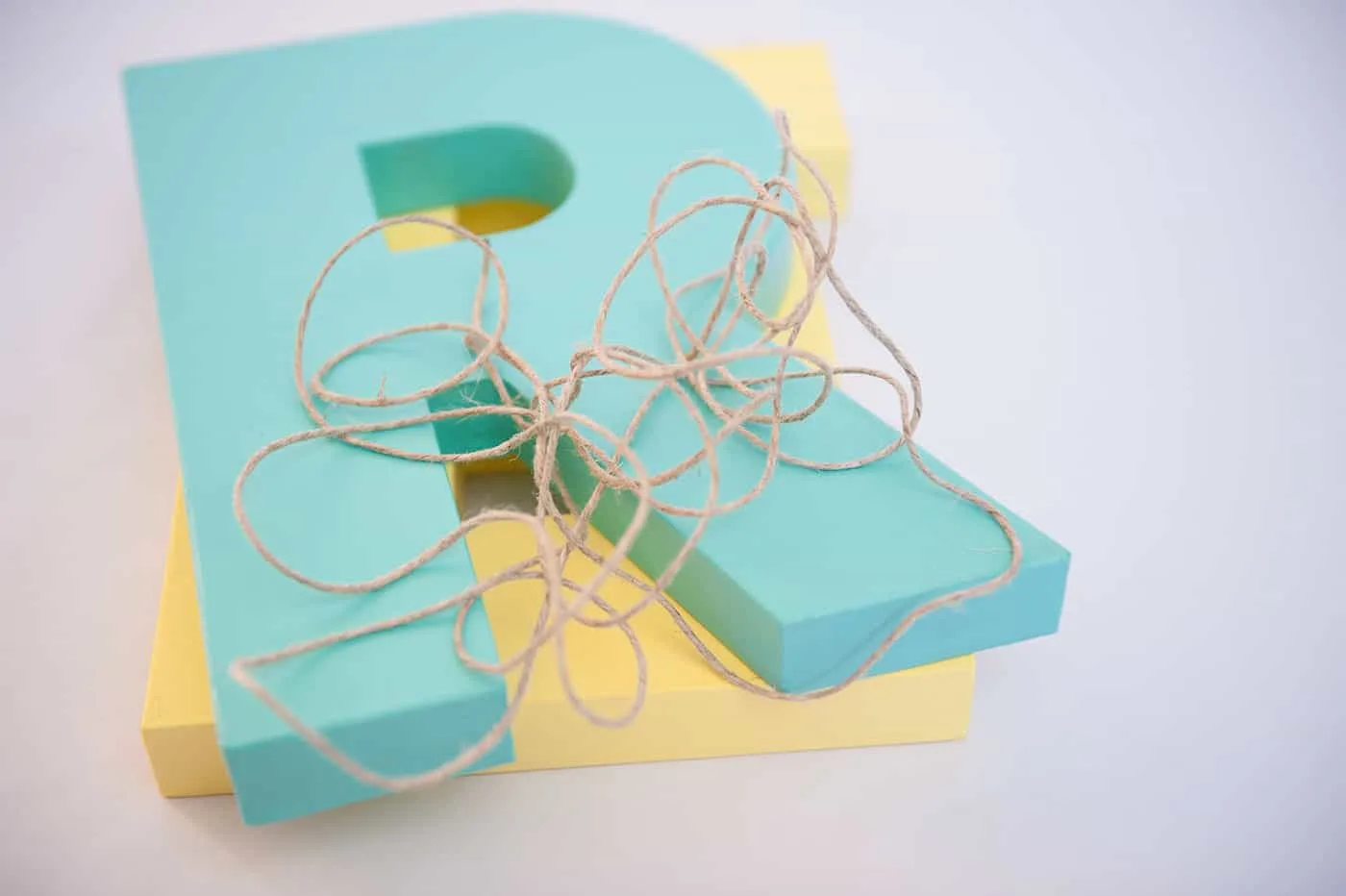 Painted wooden letters stacked and a length of twine on top