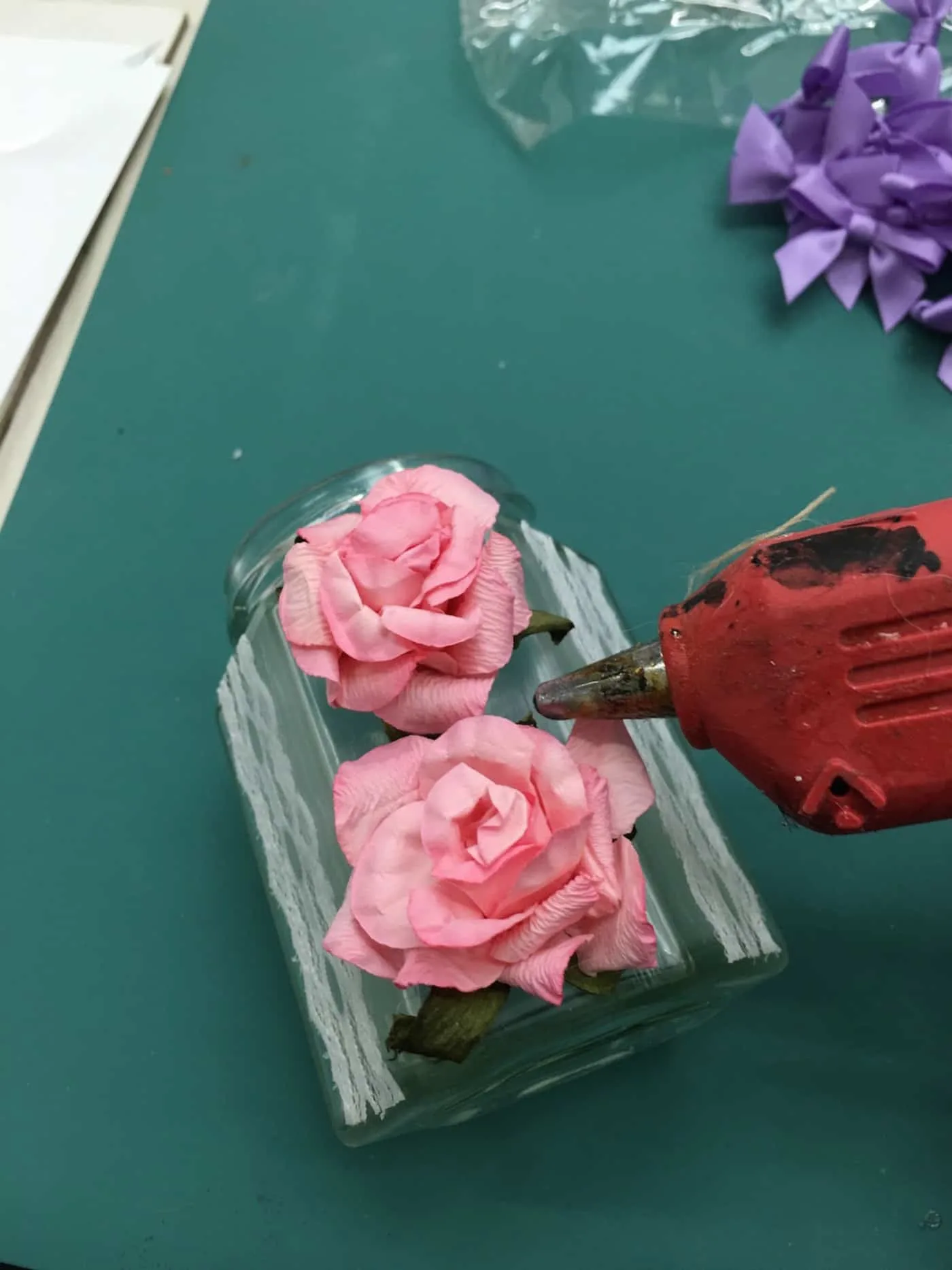 Applying roses to a jar with hot glue