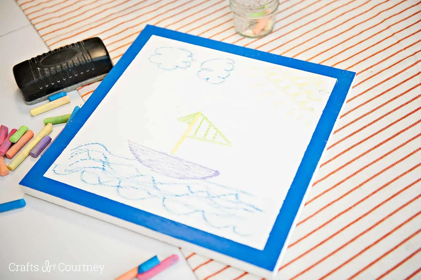 Sailboat drawn with colorful chalk on top of a white chalkboard
