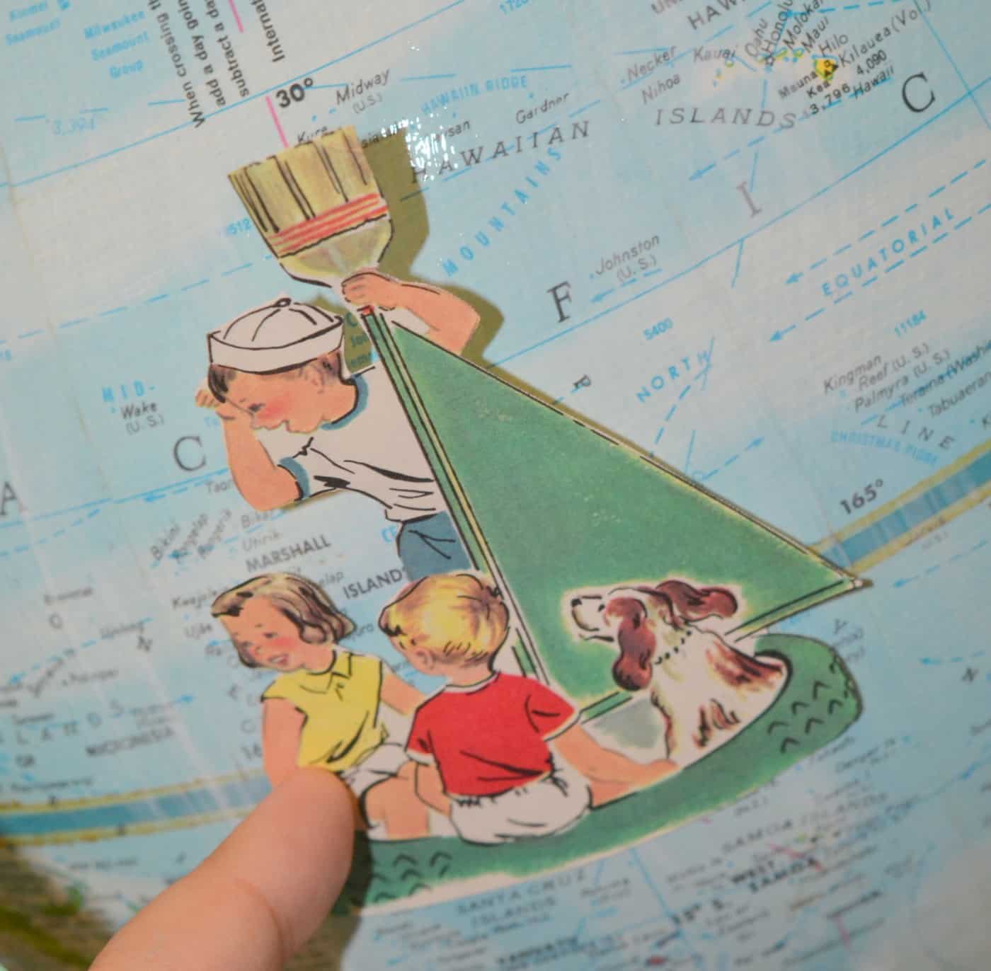 Graphic of kids in a boat being applied to the side of the globe with Mod Podge