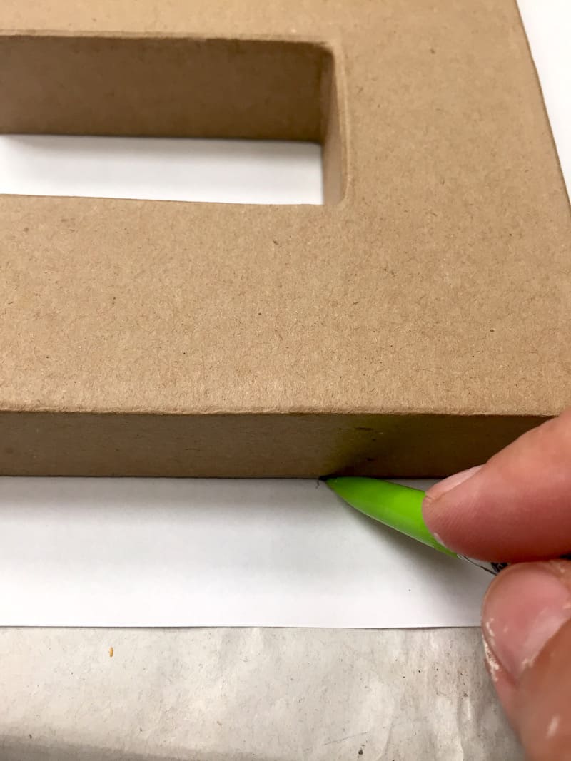 Tracing a paper mache letter onto the back of paper with a pencil