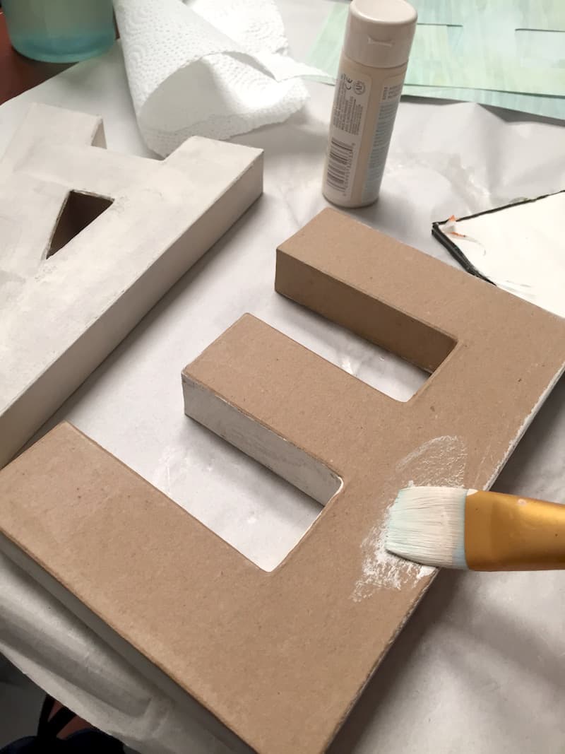 Painting the paper mache letters with warm white acrylic paint