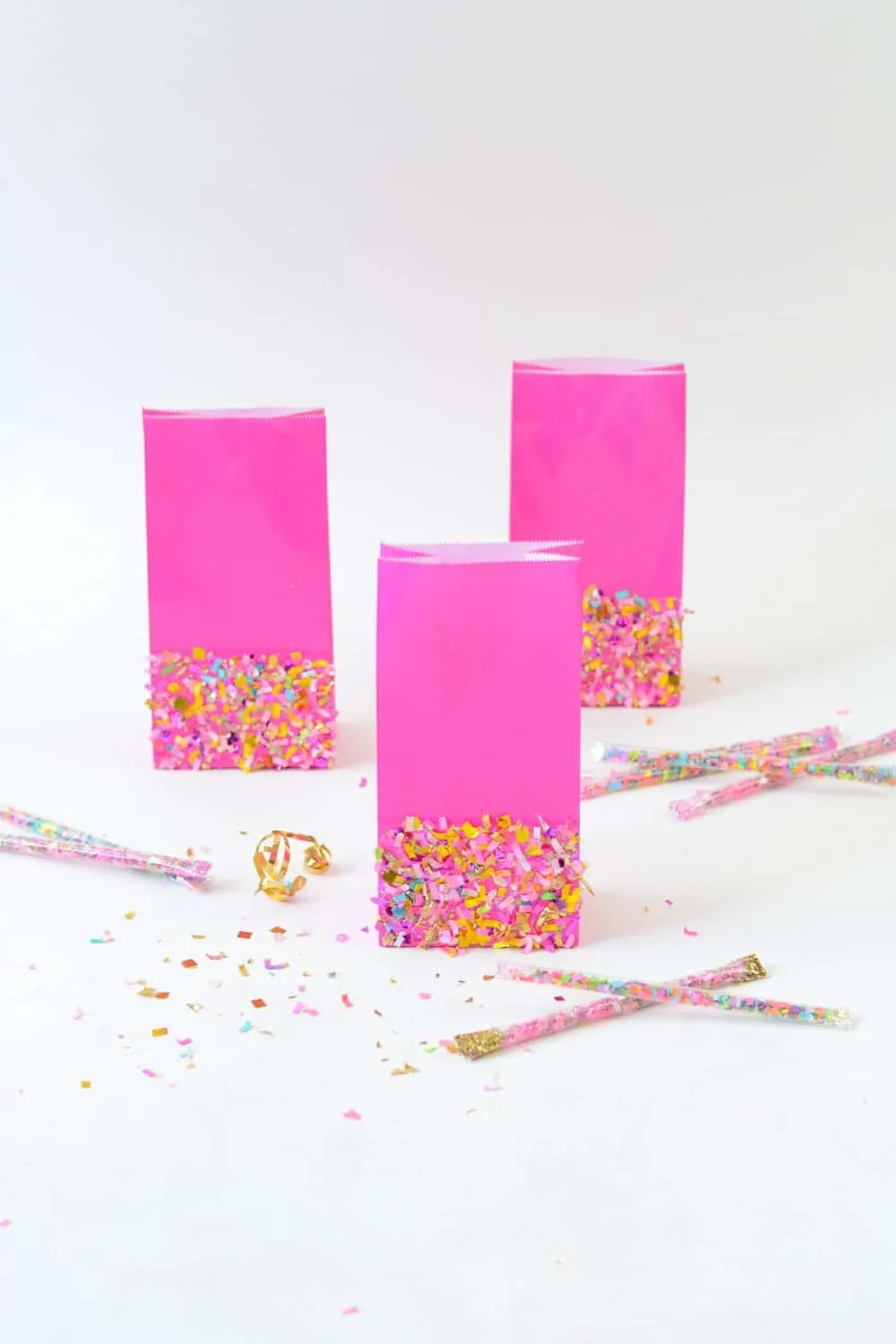 Three pink favor bags with confetti Mod Podged to the sides
