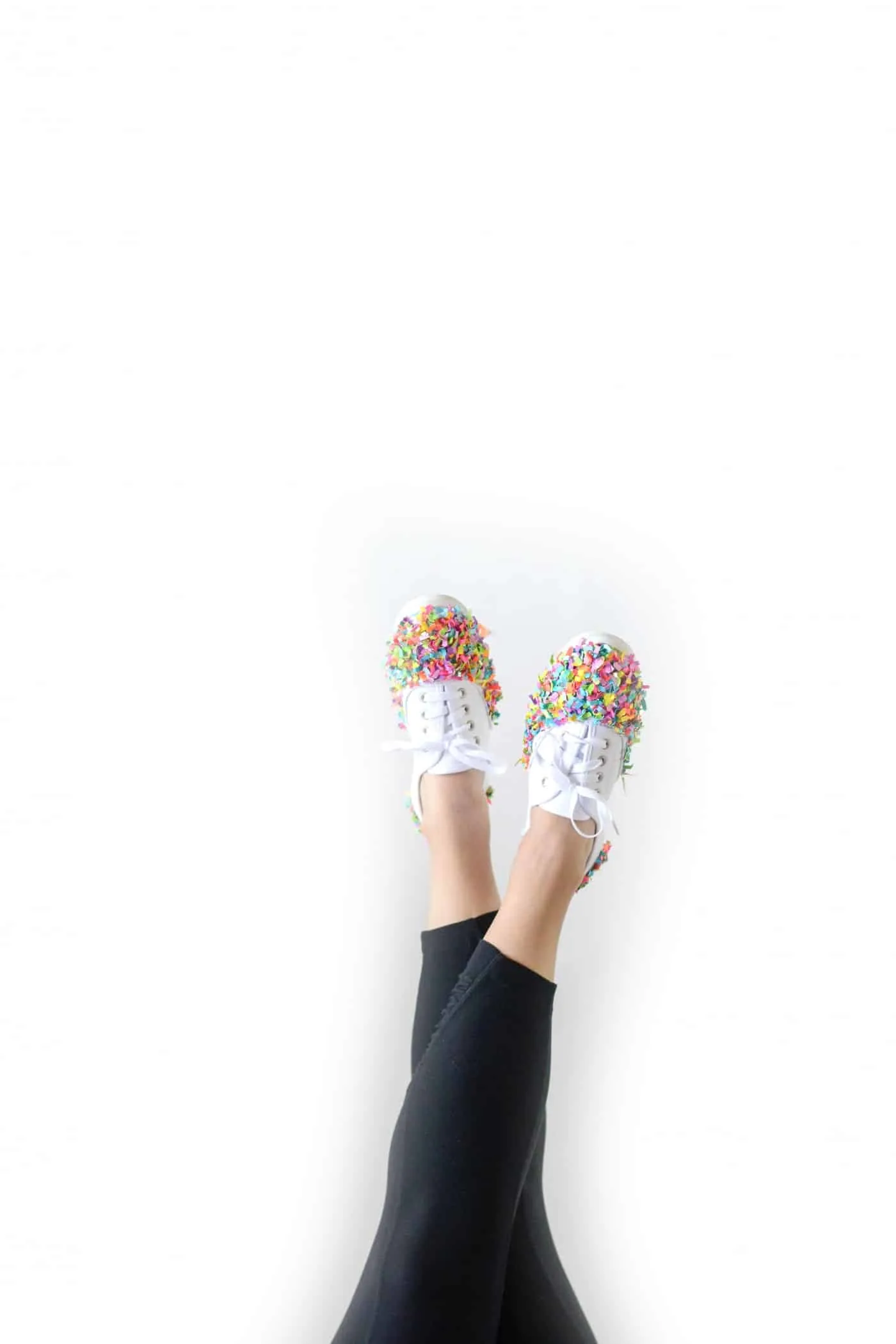 Woman's legs sticking up in the air wearing confetti shoes